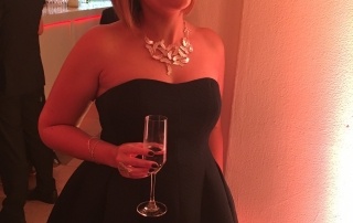 Me at the awards with glass of Bubbly, Butterfly ring on and Feather necklace